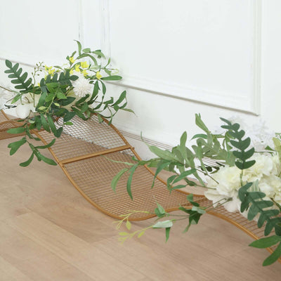 Decorative gold metal wave shelf with faux greenery and flowers.