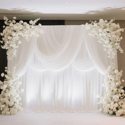 Elegant white floral backdrop with draped fabric for events and photoshoots.
