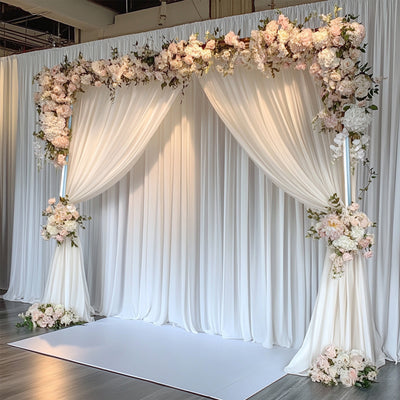 Floral archway backdrop with draped fabric and soft pastel flowers.