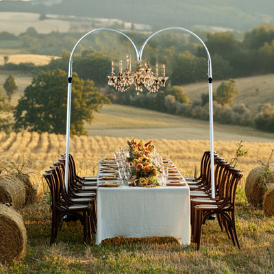 Elegant outdoor dining setup with chandelier and beautiful countryside backdrop.