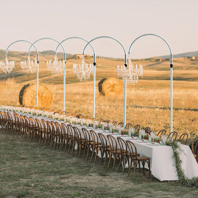 Outdoor wedding reception with elegant table settings and chandelier decor.