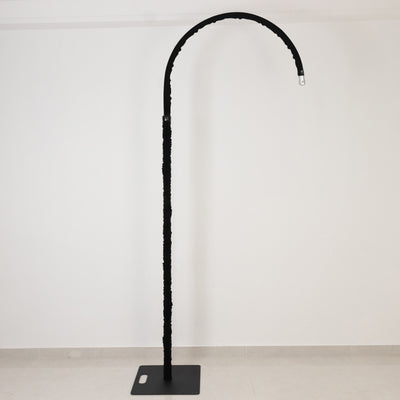 Black curved floor lamp with a minimalist design, featuring a sturdy base.