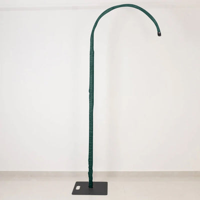 Tall green curved floor lamp on black base against a white wall