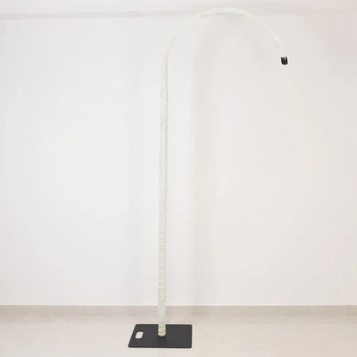 White curved floor lamp with black base on a minimal wall background