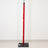 Red-wrapped vertical pole on black base against white wall