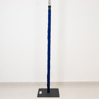 Blue padded vertical pole on a black base against a white wall