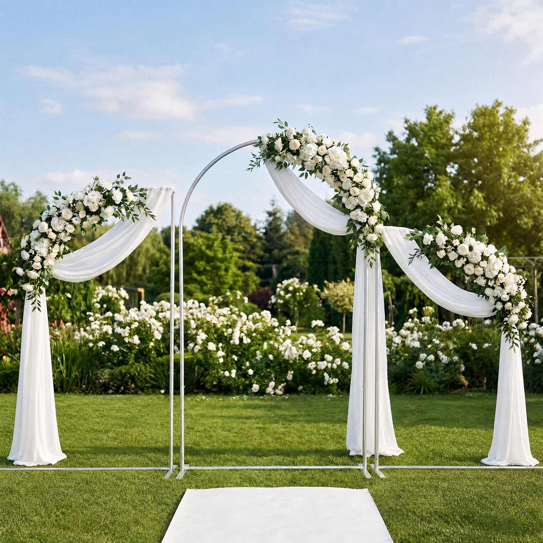 Elegant outdoor wedding arch with white floral arrangements and draped fabric
