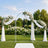 Elegant outdoor wedding arch with white floral arrangements and draped fabric