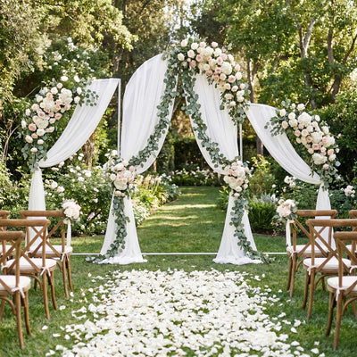 Elegant outdoor wedding ceremony arch with white drapes and floral greenery decor