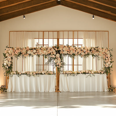 Elegant floral wedding backdrop with white drapes and tables adorned with flowers.
