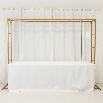 Gold wedding arch with white drapes and tablecloth, perfect for events.