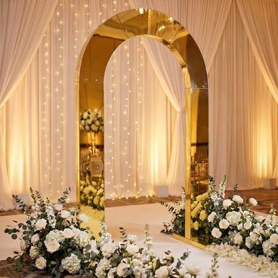 Gold mirrored wedding arch with white floral aisle decor and draped backdrop