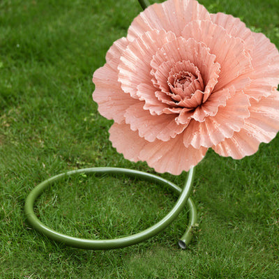 Pink giant flower sculpture made from garden hose on green grass
