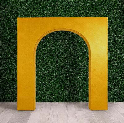 Gold decorative archway against green hedge wall and light wood floor