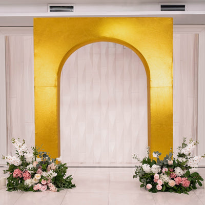 Gold archway backdrop with floral arrangements on either side.