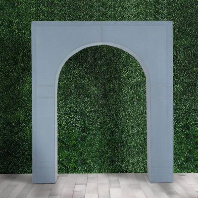 Gray decorative arch backdrop against a green hedge wall and wood floor