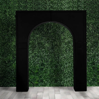 Black arched doorway against green hedge wall and gray floor paneling