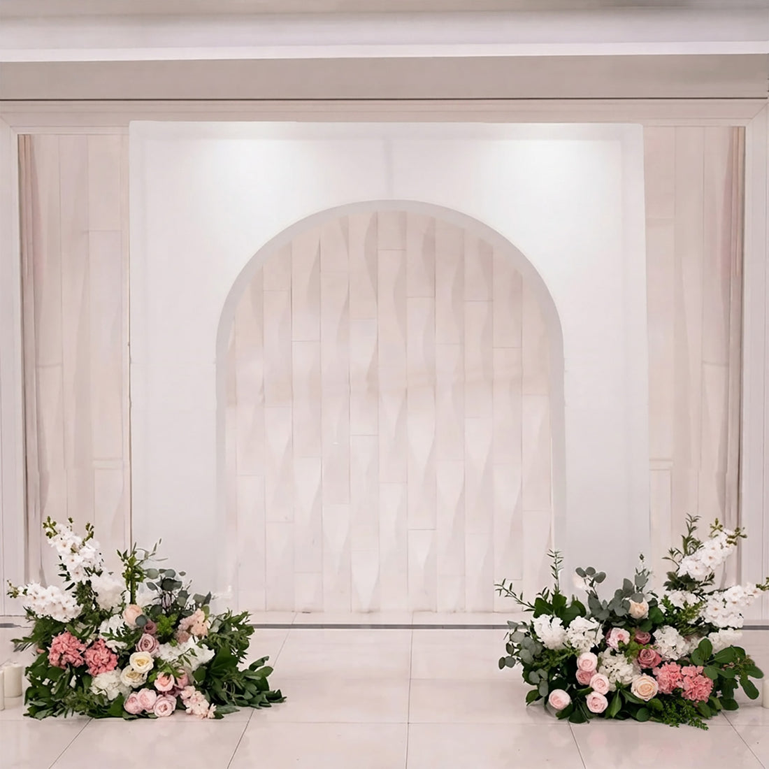 Elegant wedding backdrop with white arch and pink floral arrangements