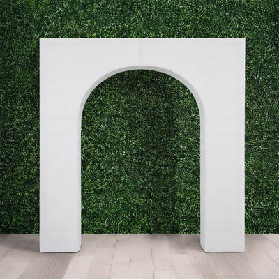 White decorative arch frame against a green foliage wall backdrop