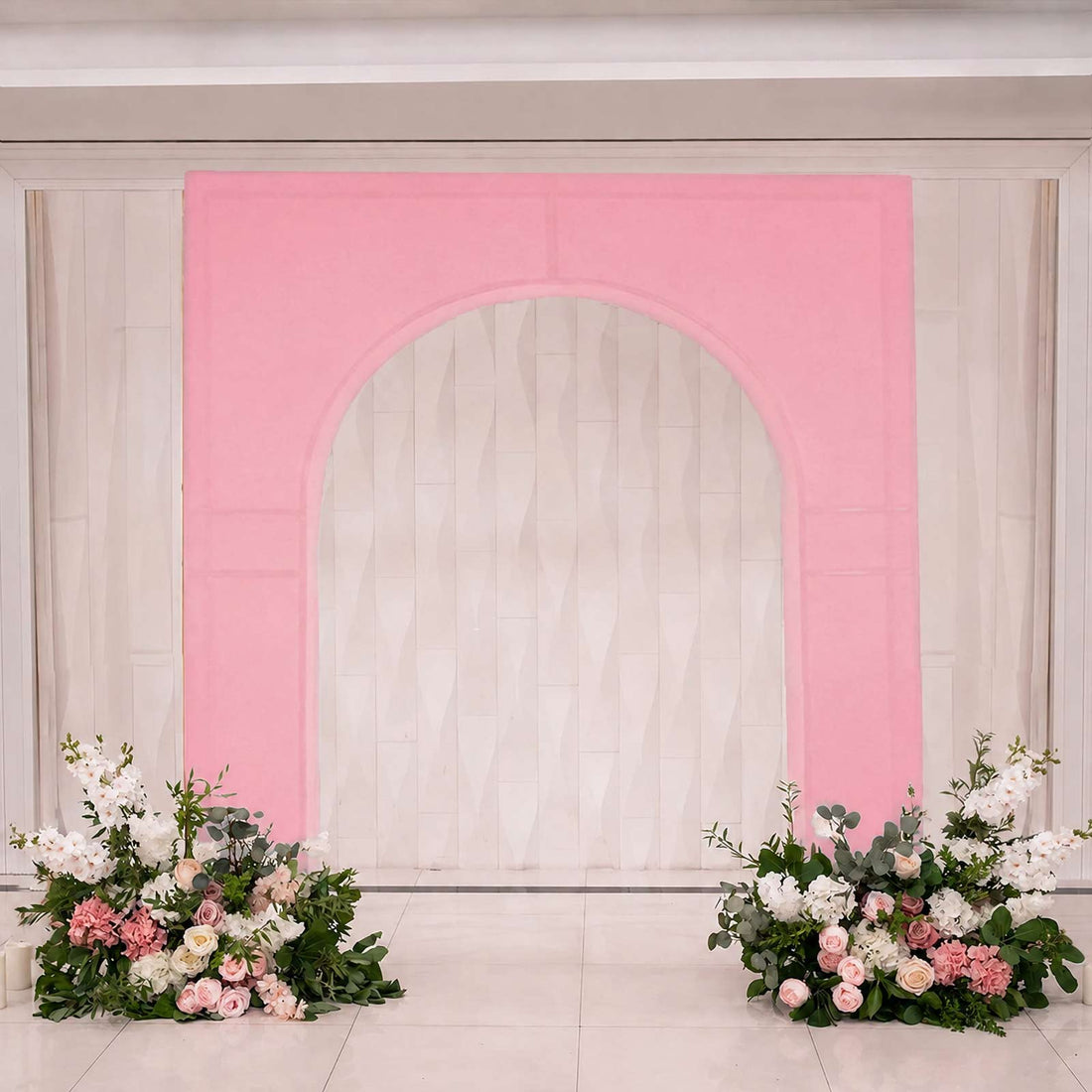 Pink floral wedding arch backdrop with white curtain and flower arrangements