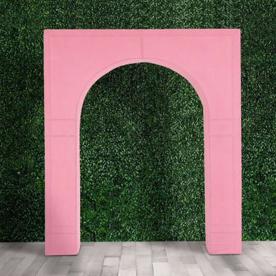 Pink inflatable arch against green hedge wall on gray floor