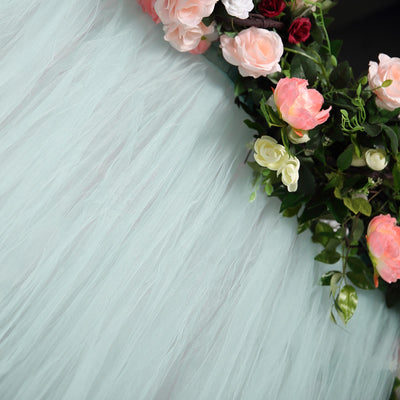 Mint tulle backdrop with floral accents in soft pink and white.