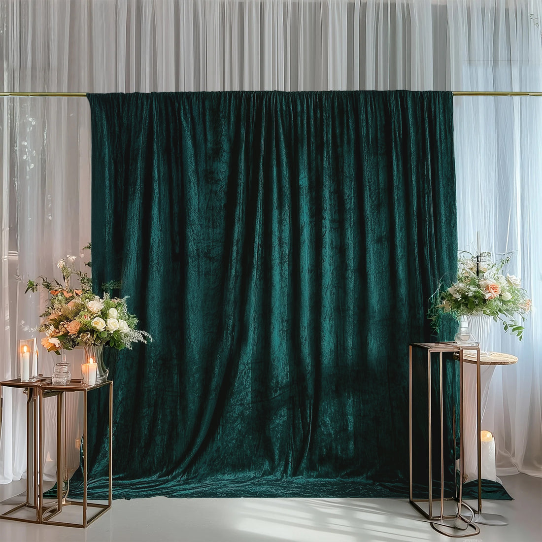 Elegant green velvet backdrop with floral arrangements and candles for events.