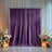 Purple velvet backdrop with floral arrangements and candles.