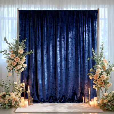 Elegant navy velvet backdrop with floral arrangements and candles for events.