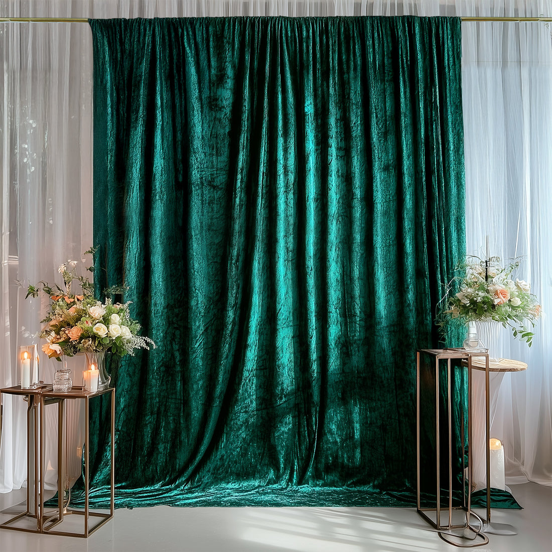 Elegant emerald green velvet backdrop with floral arrangements and candles.