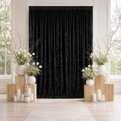 Elegant black backdrop with white floral arrangements and candles at a wedding ceremony.