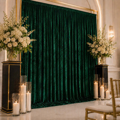 Elegant emerald green velvet wedding backdrop with white floral arrangements and candles