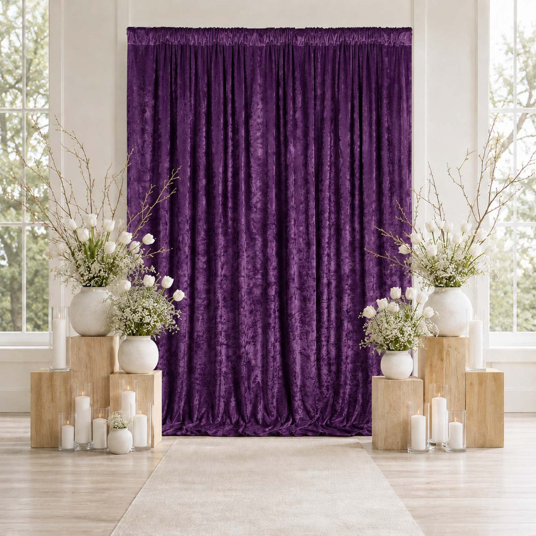 Purple draped wedding backdrop with floral arrangements and candles