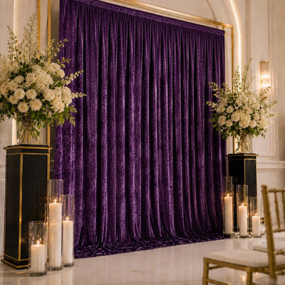 Elegant purple velvet wedding backdrop with white floral arrangements and candles