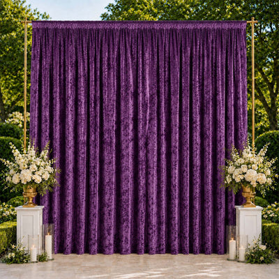 Purple draped wedding backdrop with floral arrangements and candles