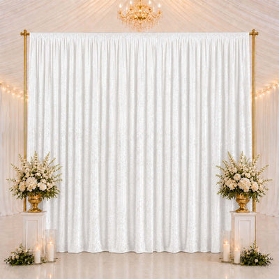 Elegant wedding backdrop with white drapes, gold frame, and floral arrangements
