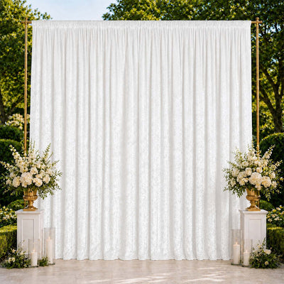 Elegant wedding backdrop with white drapery, floral arrangements, and candle decor