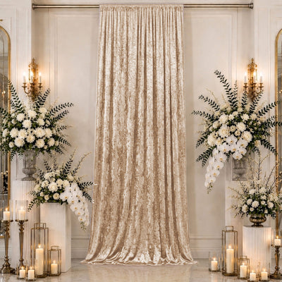 Elegant wedding backdrop with champagne velvet drape, white florals, and candles