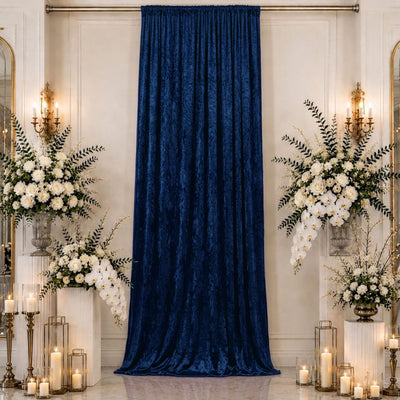 Elegant wedding backdrop with blue velvet curtain, white flowers, and candle décor