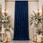 Elegant wedding backdrop with blue velvet curtain, white flowers, and candle décor