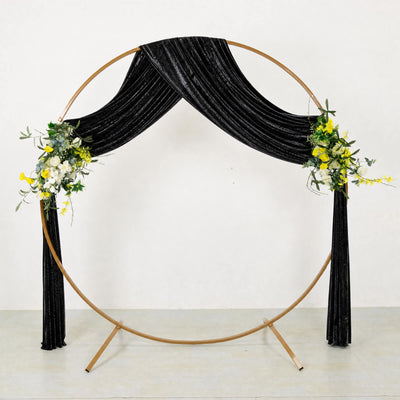 Gold circular backdrop with black velvet drapes and floral arrangements