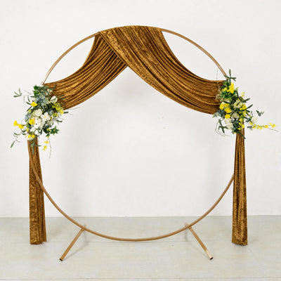 Gold wedding circle arch with velvet drape and floral arrangements