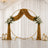 Elegant gold wedding arch with white roses, draped backdrop, and lanterns