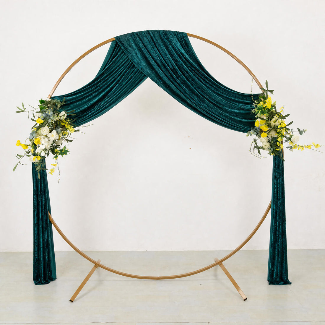 Teal velvet wedding backdrop with gold circular frame and floral arrangements