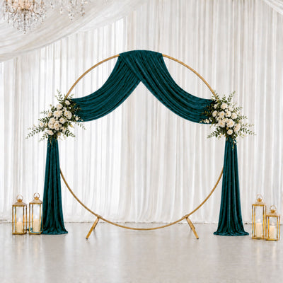Elegant wedding backdrop with emerald drapes, gold circle arch, and floral accents
