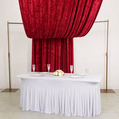 Elegant red velvet draped wedding backdrop with white table and floral centerpiece