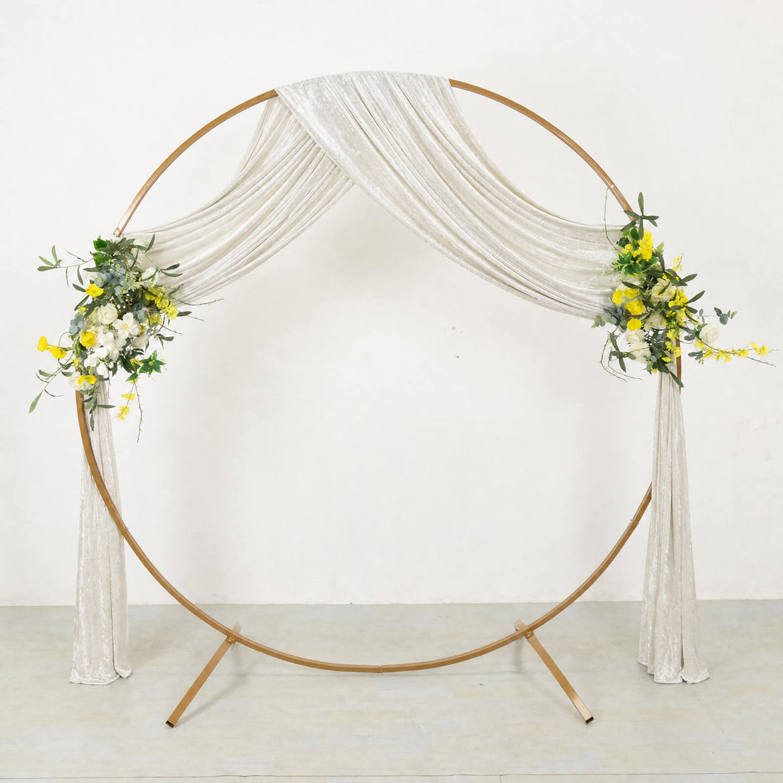 Elegant gold wedding circle arch with white drapery and floral accents