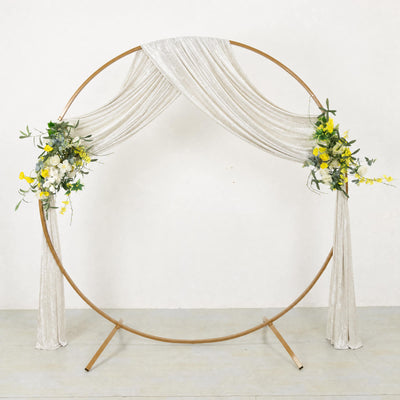 Elegant gold wedding circle arch with white drapery and floral accents