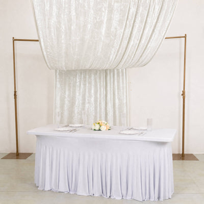 Elegant white wedding reception table with draped backdrop and gold stands