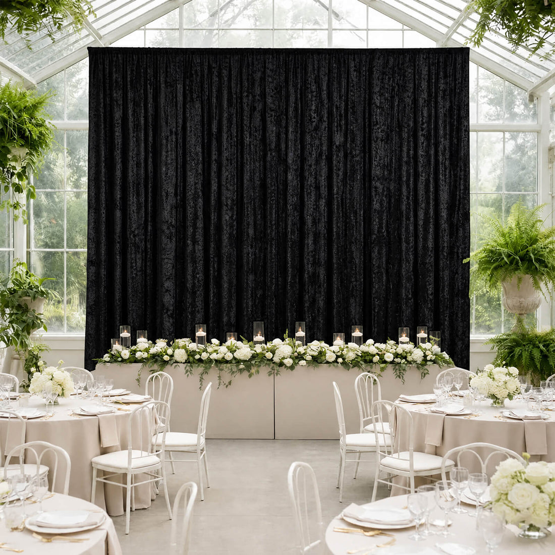 Elegant greenhouse wedding reception with black drape backdrop and white floral tablescape